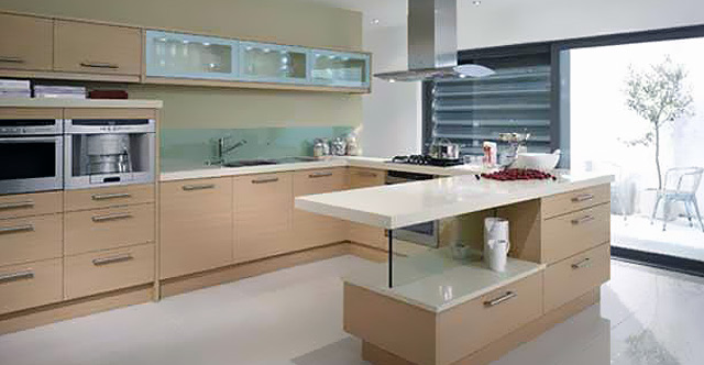 A warm oak-fronted kitchen with a peninsula island, glass upstands and an integrated wall of appliances, opening onto a courtyard.